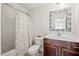 A well-lit bathroom with a shower-tub combination, white countertop, and decorative mirror at 2256 Toad Hollow Trl, Apex, NC 27502