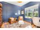 Cozy home office with blue walls, a patterned rug, comfortable seating and a bright window at 2328 Sanctuary Dr, Raleigh, NC 27606