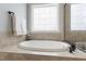 This bright bathroom features a soaking tub with tile surround and unique stain glass windows at 2661 Silver Bend Dr, Apex, NC 27539