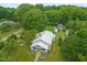 Aerial view showcasing the home, with its inviting front porch, sunny yellow accents, and lush, surrounding landscape at 2815 Orange Grove Rd, Hillsborough, NC 27278