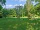 Large grassy backyard with mature trees and a partly cloudy blue sky at 2815 Orange Grove Rd, Hillsborough, NC 27278