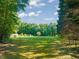 A vast green field surrounded by lush trees and a partial fence for privacy at 2815 Orange Grove Rd, Hillsborough, NC 27278