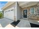Close up of front entrance featuring stone accents, a modern black door, and a two-car garage at 304 Azalea Gaze Dr, Youngsville, NC 27596