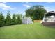 Spacious backyard with lush grass, a storage shed, and a partially covered deck at 308 E Quailwood Dr, Fuquay Varina, NC 27526