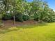 Green backyard view showcasing a sloping lawn with mature trees and lush landscaping at 324 Farrow Glen Loop, Cary, NC 27519