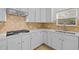 Well-lit kitchen with diamond-pattern backsplash, gas stove, and white cabinets at 324 Farrow Glen Loop, Cary, NC 27519