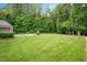 The expansive backyard features a manicured lawn, and is equipped with a pool, trampoline, and wooded perimeter at 3347 Alamance Dr, Raleigh, NC 27609