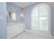 Stylish bathroom features a round mirror, white vanity, and an arched window with shutters at 3347 Alamance Dr, Raleigh, NC 27609