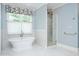 Elegant bathroom with a soaking tub, patterned tile accent wall, and a glass enclosed walk-in shower at 3347 Alamance Dr, Raleigh, NC 27609