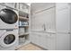 Functional laundry room with stacked washer/dryer, storage shelves, and a utility sink at 3347 Alamance Dr, Raleigh, NC 27609