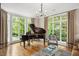 Bay window living room features a grand piano, chandelier, and comfortable seating at 3347 Alamance Dr, Raleigh, NC 27609