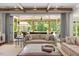 Open living room featuring neutral furniture, wooden beams, and large windows leading to a screened outdoor space at 3347 Alamance Dr, Raleigh, NC 27609