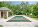A rectangular in-ground pool is surrounded by a stone patio and lush landscaped with a pool house nearby at 3347 Alamance Dr, Raleigh, NC 27609