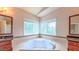Bathroom with a tiled deck tub framed by windows and framed mirrors and vanities at 3408 Mount Pisgah Way, Cary, NC 27519