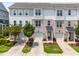 Three-story townhomes showcasing gray, white, and brick exteriors, small trees, and driveways leading to garages at 364 Skymont Dr, Holly Springs, NC 27540