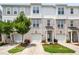 Three-story townhomes showcasing gray, white, and brick exteriors, small trees, and driveways leading to garages at 364 Skymont Dr, Holly Springs, NC 27540