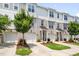 Three-story townhomes showcasing gray, white, and brick exteriors, small trees, and driveways leading to garages at 364 Skymont Dr, Holly Springs, NC 27540