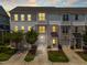Three-story townhomes showcasing gray, white, and brick exteriors, small trees, and driveways leading to garages at 364 Skymont Dr, Holly Springs, NC 27540