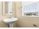 Bright powder room with pedestal sink, mirror, and window with natural light at 364 Skymont Dr, Holly Springs, NC 27540