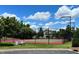 View of an outdoor tennis court with green and red surfaces and a surrounding fence at 407 Elm Farm Pl, Morrisville, NC 27560