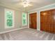 Bedroom featuring neutral paint, carpet, two large closets, and natural light from two windows at 4204 Thetford Rd, Durham, NC 27707