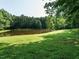 Picturesque view of a serene pond with a well-maintained green lawn and a backdrop of mature trees at 4204 Thetford Rd, Durham, NC 27707