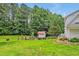 A lush backyard featuring a charming playhouse, green lawn, and wooded area at 4702 Pleasant Green Rd, Durham, NC 27705