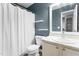Bathroom features blue walls, white vanity, and toilet with white shower curtain and shelving at 50 Rainwood Ct, Louisburg, NC 27549