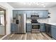 Well-equipped kitchen with stainless steel appliances and custom blue cabinets at 50 Rainwood Ct, Louisburg, NC 27549