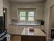 Charming kitchen with white cabinetry and a view of the lawn through double windows above the sink at 500 W Main St, Benson, NC 27504