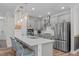 Modern kitchen boasts stainless steel appliances, white countertops, pendant lighting, and bar seating for casual dining at 512 Teal Lake Dr, Holly Springs, NC 27540