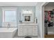 Bright bathroom featuring a soaking tub, white vanity, and a view into the spacious walk-in closet at 517 Myrna Ln, Wake Forest, NC 27587