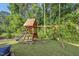 A wooden playset with slide and swing set sits amidst a green, well-maintained lawn in the spacious backyard at 517 Myrna Ln, Wake Forest, NC 27587