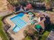 Aerial view showcasing the community pool with lap lanes, lounge chairs, umbrellas, and surrounding buildings with parking at 5216 Sunset Fairways Dr, Holly Springs, NC 27540