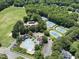 Aerial view of community amenities featuring tennis courts, swimming pool, parking, and a golf course in a wooded setting at 5216 Sunset Fairways Dr, Holly Springs, NC 27540