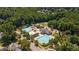 Aerial view of community amenities featuring multiple pools, water park, umbrellas, and parking in a wooded setting at 5216 Sunset Fairways Dr, Holly Springs, NC 27540