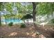 A serene lakeside setting with a hammock, lush greenery, and clear turquoise water. A peaceful escape at 5216 Sunset Fairways Dr, Holly Springs, NC 27540