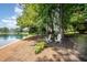 Lakeside backyard featuring white rocking chairs and lush greenery for serene relaxation by the water at 5216 Sunset Fairways Dr, Holly Springs, NC 27540