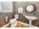 Cozy half-bath features pedestal sink, a round mirror, and neutral-toned walls at 5216 Sunset Fairways Dr, Holly Springs, NC 27540