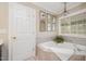 Well-lit bathroom showcasing a soaking tub with a window and vanity with mirrors at 5216 Sunset Fairways Dr, Holly Springs, NC 27540