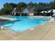 Community swimming pool with lap lanes, lifeguard chair, lounge chairs, and surrounding landscaping with clear blue sky at 5216 Sunset Fairways Dr, Holly Springs, NC 27540