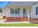 Close-up of a front porch with brick accents, white railings, and a charming entrance door at 5328 Trackway Dr, Knightdale, NC 27545