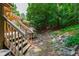 View of the backyard with a stone-lined path and deck with wooden stairs at 60 Stoneridge Rd, Durham, NC 27705