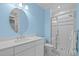 Modern bathroom with a white vanity, round mirror, and glass-enclosed shower showcasing black-and-white tile at 622 Sunset Ave, Apex, NC 27502