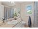 Bright bathroom with vanity, large mirror, natural light, and shower with patterned curtain at 6304 Ansley Ln, Raleigh, NC 27612