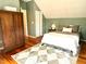 Cozy bedroom features a bed with a white coverlet, accenting the hardwood floors and green walls at 6304 Ansley Ln, Raleigh, NC 27612