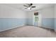 Carpeted bedroom with blue paneling, ceiling fan, and natural light from a bright window at 6304 Ansley Ln, Raleigh, NC 27612