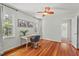 Bright bedroom with hardwood floors, fan, a desk with a chair, and natural light from two windows at 6304 Ansley Ln, Raleigh, NC 27612