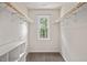 Bright walk-in closet with carpet flooring, built-in shelving, and natural light from a window at 6304 Ansley Ln, Raleigh, NC 27612