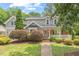 Charming gray two-story home with brick accents, a front porch, and a well-manicured lawn and landscaping at 6304 Ansley Ln, Raleigh, NC 27612